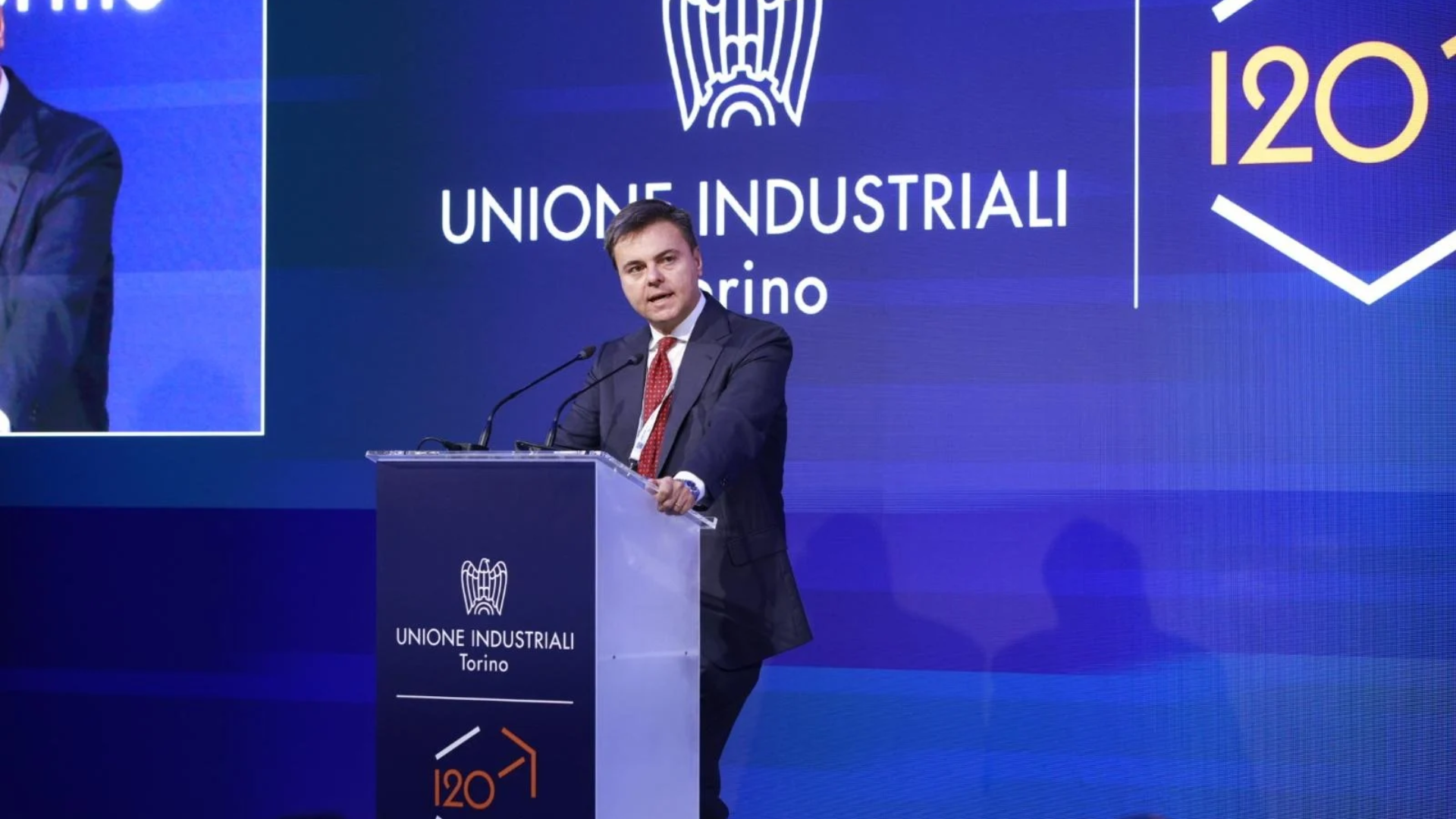 Intervento dal podio di Marco Gay all’assemblea dell’Unione Industriali Torino, con il logo celebrativo dei 120 anni sullo sfondo.